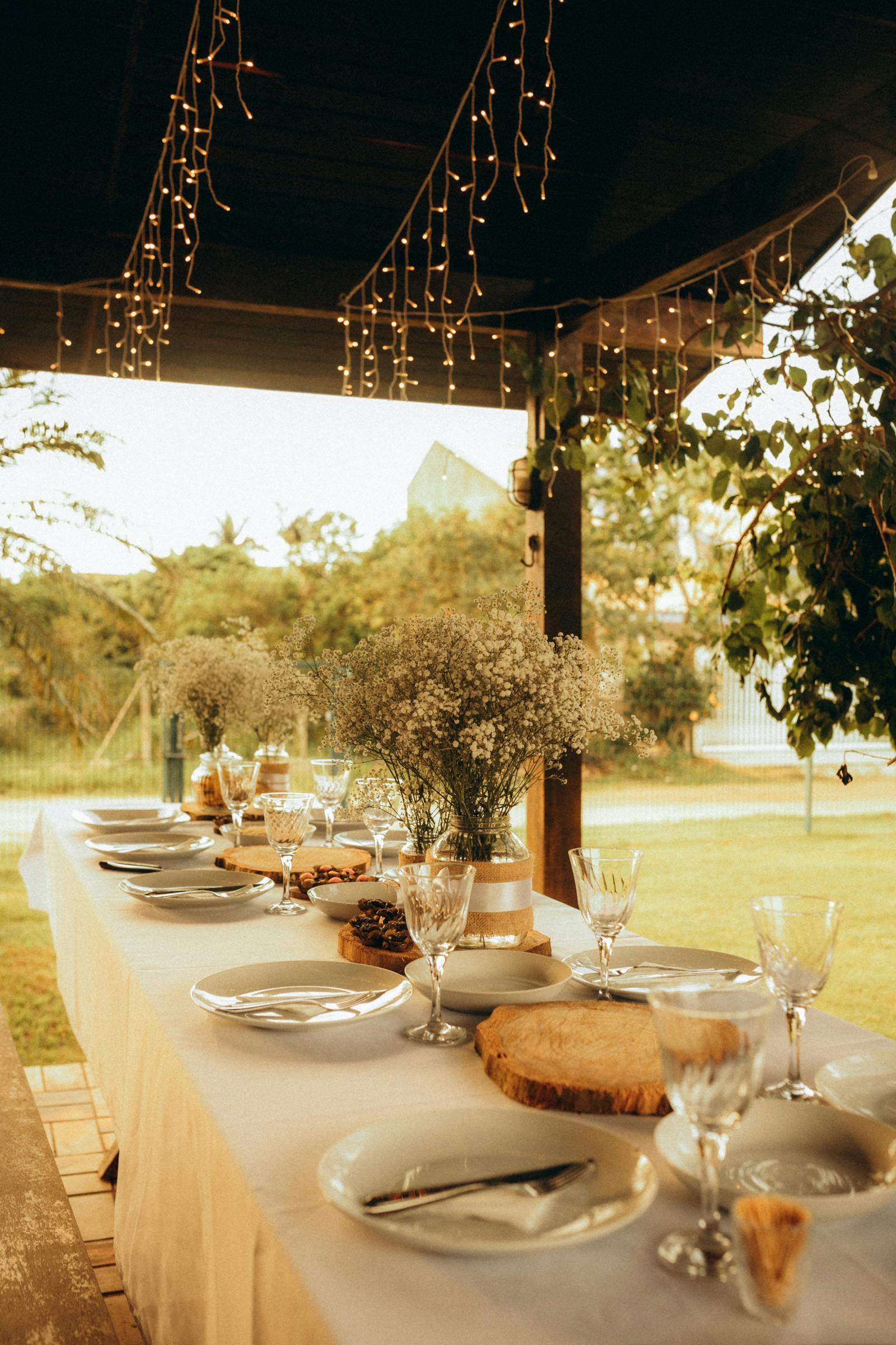 The vancroft western terrace at sunset — long linen-covered tables with wine glasses set for ten under a wisteria arbour.